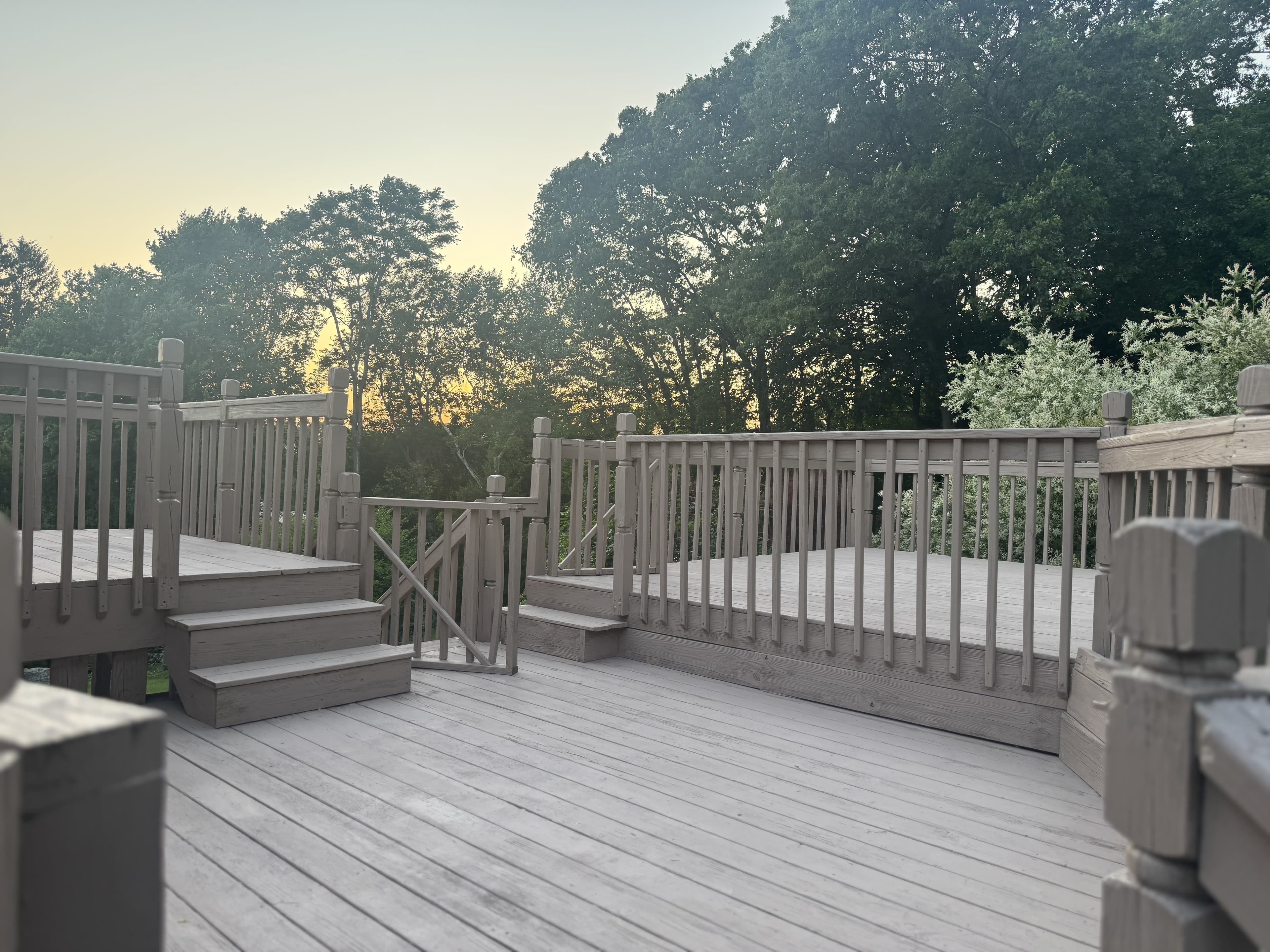 A freshly restored deck overlooking trees at sunset